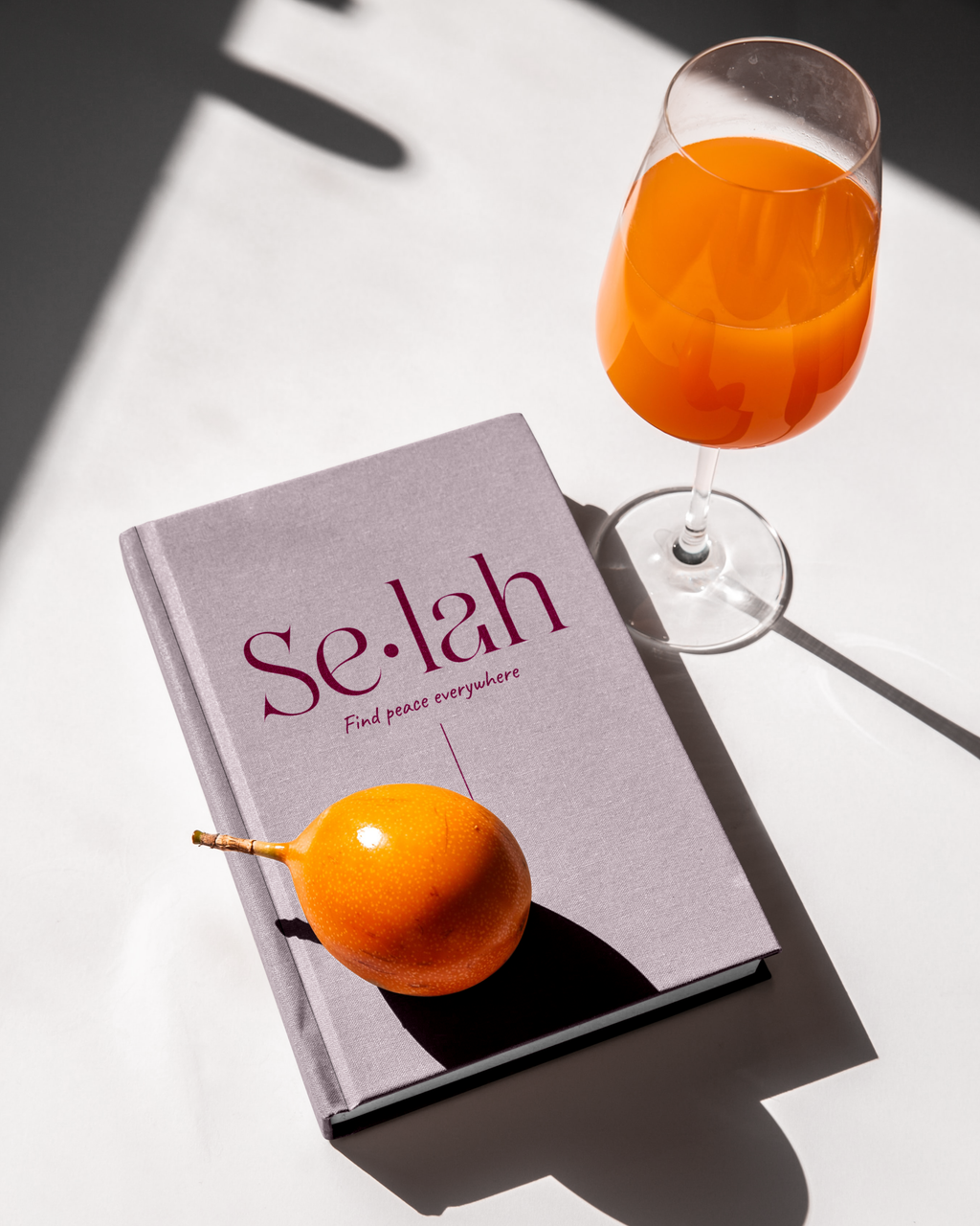 Planner Selah rose posé sur une table blanche avec un verre de jus de fruits